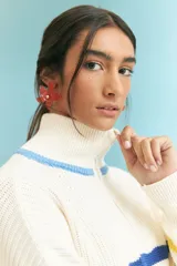 Sweater de punto grueso color crudo, con cuello alto con cierre de cremallera y rayas horizontales en azul, amarillo y rojo.