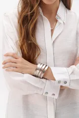 Camisa negra de manga larga con cuello clásico y cierre frontal con botones. Presenta costuras decorativas en color blanco.