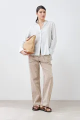 Camisa oversize celeste y blanca a rayas verticales, con cuello mao y mangas largas con puños abotonados.