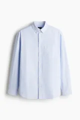 Camisa de vestir celeste y blanco a rayas verticales, de corte regular fit, con cuello abotonado, bolsillo en el pecho y mangas largas con puños abotonados.