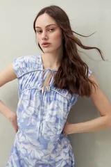 Vestido largo con estampado floral celeste y blanco, escote ajustable con lazo y frunce en la parte superior.