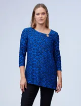 Blusa de tejido texturado color negro, con escote en V descentrado y aplique de aro metálico, terminación de ruedo asimétrico.