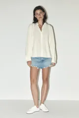 Minifalda de jean azul con tiro medio, cinco bolsillos, roturas y terminación desflecada.