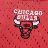 Camiseta deportiva roja de básquet, con cuello y mangas con ribete blanco y negro. Estampado frontal con el nombre "Chicago" en letras negras con borde blanco y el logo del equipo Chicago Bulls. Cierre frontal con botones a presión.
