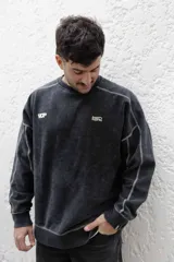 Buzo negro de frisa 100% algodón con calce oversize y lavado gastado. Presenta costuras a contratono, recortes y logos estampados en el frente y en el puño.