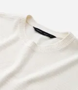 Remera de mangas cortas color crema, confeccionada con 50% algodón y 50% poliéster, con cuello redondo y tejido texturizado.