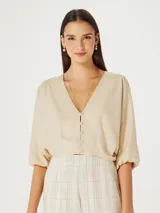 Blusa beige con escote en V, mangas 3/4 abullonadas y cierre frontal con botones.