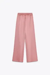 Pantalón de tiro alto color rosado, con cintura elástica ajustable con cordones, bolsillos delanteros y pernera ancha. Tejido con efecto arrugado.