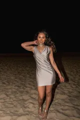 Vestido corto dorado con escote cruzado, sin mangas y abertura en la cintura.