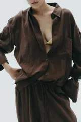 Camisa marrón de algodón, corte amplio, con cuello solapa, manga larga con puños, bolsillo de parche en el pecho, pinzas en la espalda y cierre frontal con botones.