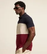 Polo de hombre de corte regular, confeccionada en algodón, con cuello clásico, mangas cortas y diseño de bloques de color: azul marino en la parte superior, blanco en el centro y rojo borgoña en la parte inferior.