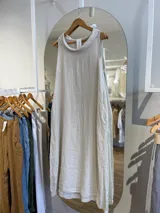 Vestido largo de lino color celeste, sin mangas y con cuello buche. Presenta un diseño de corte holgado con bolsillos laterales.