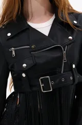 Campera corta negra estilo biker con cierre cruzado, cinturón con hebilla y flecos largos.