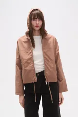 Campera de corte holgado en color tostado, confeccionada en poliamida. Presenta cuello alto, cierre frontal con cremallera, bolsillos laterales con cierre y cordón ajustable en el ruedo.