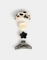 Set de cuatro broches para el pelo con diferentes diseños: uno con forma de mandíbula con estampado de vaca, uno con forma de mandíbula liso color crema, uno con forma de flor negro y uno con forma de mandíbula con estampado de leopardo.