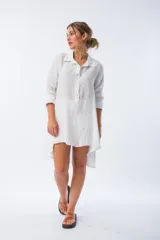 Camisa blanca de lino con botones de nácar, corte amplio y largo irregular.