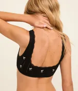 Soutien top negro seamless y texturizado, con breteles anchos fijos, escote cuadrado en la espalda, detalle de encaje y bordados de lacitos.