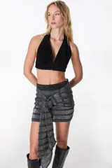 Top corto marrón de cuero con escote halter y espalda descubierta.