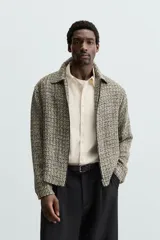 Sobrecamisa de hombre regular fit confeccionada en tejido con estructura irregular en tonos beige, marrón y negro. Tiene cuello solapa, manga larga con puños abotonados, bolsillos laterales y cierre frontal con cremallera.