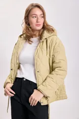 Campera capitoneada color verde claro, con capucha y cierre frontal con botones a presión. Tiene bolsillos laterales y cordón ajustable en el ruedo.