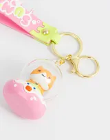 Llavero con dije de gatito dentro de una burbuja transparente y base rosa, con gancho dorado. Incluye un strap de silicona rosa con detalles en verde y la palabra "Summer".