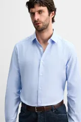 Camisa celeste de corte slim fit, confeccionada en tejido de algodón. Tiene cuello italiano, mangas largas con puños abotonados y cierre frontal con botones.