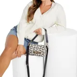 Cartera bandolera Guess Carrboro chica, color crudo con estampado del logo de la marca en azul marino. Tiene correa de hombro ajustable y desmontable en azul marino y aplique dorado con el nombre de la marca en el frente.