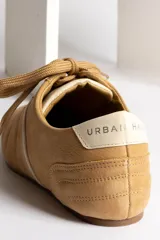 Zapatillas acordonadas color beige con detalles en blanco.