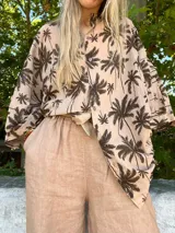 Camisa beige con estampado de palmeras marrones, de corte holgado y manga corta.