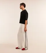 Pantalón wide leg de helanca color blanco, con cintura elástica ajustable con cordón, bolsillos laterales, raya lateral negra y bajo ajustable.