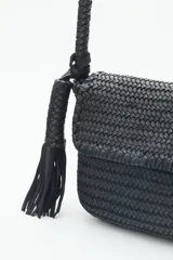Cartera bandolera negra de cuero vacuno trenzado, con acceso superior con cierre metálico, interior forrado con bolsillos y correa de hombro trenzada.