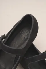Zapato estilo Mary Jane color marrón, de cuero, con punta redondeada y tira sobre el empeine con hebilla.