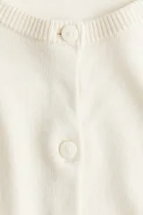 Cárdigan de punto fino color crema, con cuello redondo, botones frontales y mangas largas.