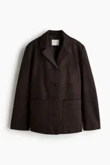 Campera tipo blazer o chaqueta de tejido suave con acabado cepillado, color marrón oscuro. Presenta solapas de muesca, cierre frontal de tres botones y dos bolsillos parche grandes en la parte delantera inferior.