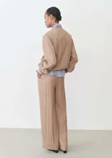 Chaqueta bomber color beige con cierre frontal, cuello mao y puños elásticos.