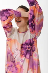 Vestido corto con vuelo de satén con maxi estampado floral combinado con organza semitransparente con líneas en el canesú. Tiene manga larga abullonada y lazo en la espalda para anudar.