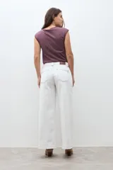 Pantalón de jean blanco crudo de tiro alto, corte culotte ancho y largo, con costuras en color rojizo.