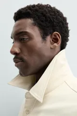 Sobrecamisa color crudo de corte regular fit, confeccionada en tejido con mezcla de viscosa. Tiene cuello solapa, manga larga con puños abotonados, bolsillo de parche en el pecho, bajo ajustable con cordones y cierre frontal con botones.