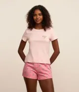 Conjunto de pijama short doll color rosa, compuesto por una remera de manga corta con estampado de texto y un short con estampado de flores.