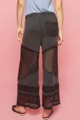 Pantalón negro de corte relajado con cintura elástica y detalles de red en los laterales y en el ruedo.