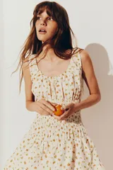 Vestido corto blanco con estampado de naranjas, breteles anchos y escote en U. Presenta frunces en el busto y falda con volados.