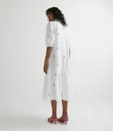 Vestido camisero midi blanco con estampado de flores rosas y celestes, manga corta abullonada, cuello camisero, abotonado al frente y falda con volantes.