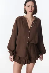 Camisa beige de manga larga con botones y detalles de encaje.