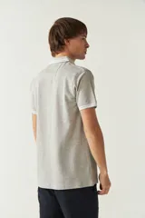 Remera cuello polo gris melange de manga corta, corte regular, con detalles de doble línea blanca en cuello y mangas, logo estampado en el pecho y confección en algodón.