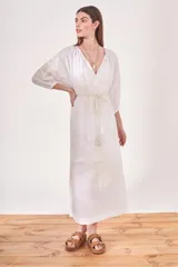 Vestido túnica largo color blanco, con escote en V, mangas 3/4 y bordado floral en el frente y las mangas. Incluye lazo de ajuste en la cintura con borlas.