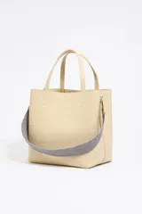 Bolso tote negro de cuero vacuno con doble asa corta y correa de tela extraíble. Interior con tres compartimentos y bolsillo con cremallera. Logo metálico de la marca en el frente.