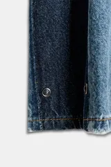 Jeans de tiro medio y corte barrel, confeccionados en denim de lavado celeste claro, con paneles laterales de denim azul oscuro a contraste. Presentan cinco bolsillos y cierre frontal con cremallera y botón.