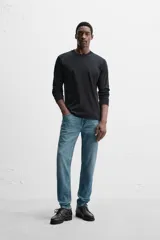 Pantalón de jean azul oscuro, corte slim fit, tiro medio, cinco bolsillos, tejido elástico y efecto lavado.