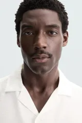 Camisa de calce relajado confeccionada en tejido fluido de mezcla de viscosa, color blanco. Presenta cuello bowling, manga corta, aberturas laterales en el bajo y cierre frontal con botones al tono.