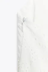 Vestido midi blanco con bordados florales perforados, escote en V, sin mangas y tirantes cruzados en la espalda.